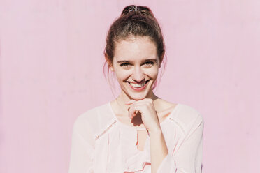 Porträt einer lächelnden jungen Frau vor einer rosa Wand - UUF15739