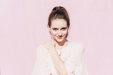 Portrait of smiling young woman in front of pink wall stock photo