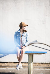 Smiling young woman with cell phone sitting on table tennis table - UUF15748