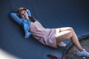 Smiling young woman lying outdoors with closed eyes - UUF15761