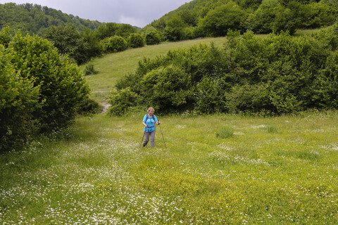 Albanien, Kreis Shkoder, Albanische Alpen, Theth-Nationalpark, Wanderin geht über Blumenwiese, lizenzfreies Stockfoto