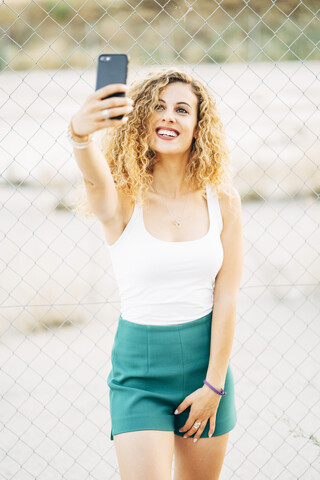 Porträt einer blonden jungen Frau, die ein Selfie mit ihrem Mobiltelefon macht, lizenzfreies Stockfoto