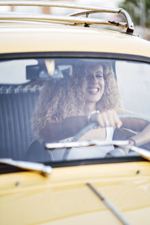 Porträt einer lachenden blonden Frau, die einen Oldtimer fährt - OCMF00027