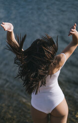 Back view of jumping woman at lake - OCMF00038