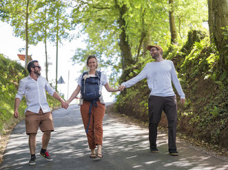 Happy parents with baby girl strolling hand in hand with a friend - LAF02119