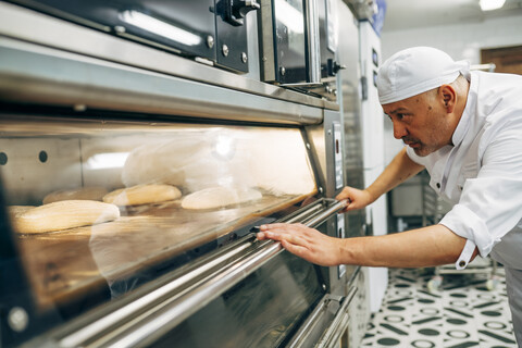 Bäcker bei der Vorbereitung des Ofens für die Herstellung von Brot, lizenzfreies Stockfoto