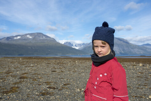 Norwegen, Mädchen mit Pudelmütze und roter Jacke am Strand, Lyngenfjord - PSIF00136