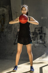 Porträt eines selbstbewussten Sportlers, der einen Basketball an die Wand hält - CAVF52360