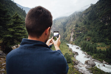 Rear view of male hiker photographing river amidst mountains at Sagarmatha National Park - CAVF52388