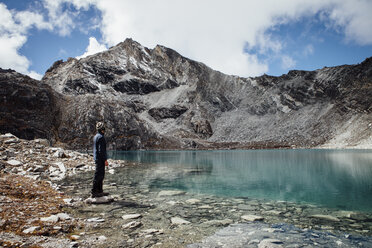 Seitenansicht eines Mannes, der am Seeufer vor einem bewölkten Himmel im Sagarmatha-Nationalpark steht - CAVF52392