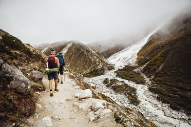 Rear view of friends with backpacks hiking at Sagarmatha National Park during foggy weather - CAVF52397