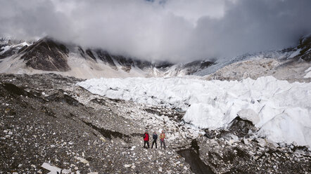 Rear view of hikers standing on landscape against cloudy sky during winter - CAVF52410