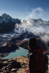 Hiker with backpack looking at mountains against blue sky during sunny day - CAVF52413