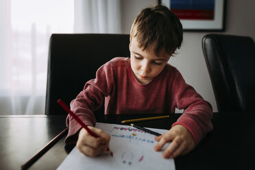 Boy drawing with colored pencil on paper at home - CAVF52484