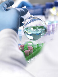 Cropped hand of scientist holding chemical in container for medical testing - CAVF52489