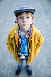 Hochformatiges Porträt eines Jungen mit Kamera auf der Straße stehend - CAVF52497