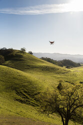 Drohne fliegt über Hügel gegen den Himmel an einem sonnigen Tag - CAVF52498