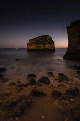 Scenic view of rock formation in sea against sky at night - CAVF52543
