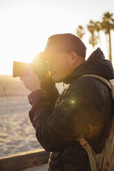 Mann beim Fotografieren am Strand gegen den klaren Himmel bei Sonnenuntergang - CAVF52552