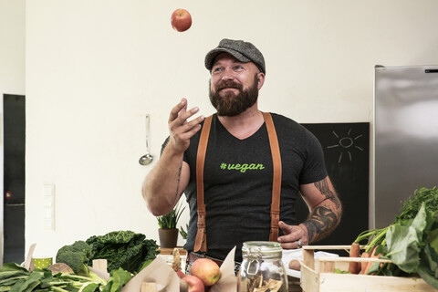 Veganer, der in seiner Küche mit Äpfeln jongliert, lizenzfreies Stockfoto