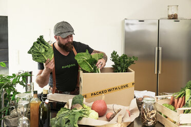 Mature man with delivery service packing organic vegetables in cardboard - REAF00362