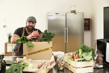 Mature man with delivery service packing organic vegetables in cardboard - REAF00366