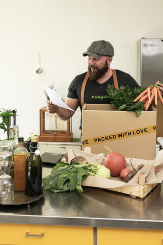 Älterer Mann mit Lieferservice verpackt Bio-Gemüse in Karton, lizenzfreies Stockfoto