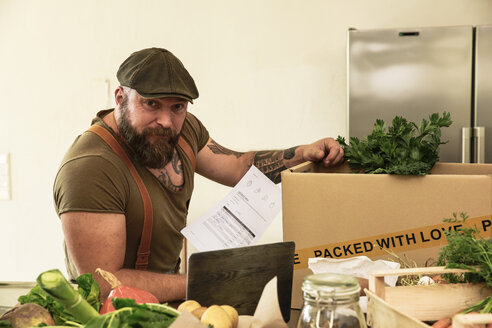 Mature man with delivery service packing organic vegetables in cardboard - REAF00374