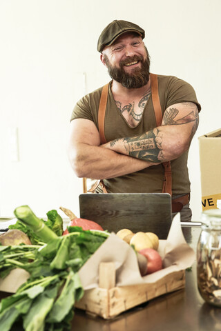 Inhaber eines Lieferdienstes für Biogemüse, der stolz in seiner Küche steht, lizenzfreies Stockfoto