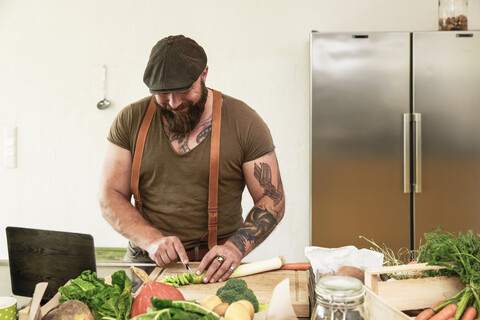 Älterer Mann probiert vegetarische Online-Rezepte aus, lizenzfreies Stockfoto