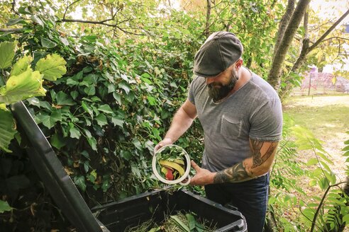 Mature man discarding kitchen scraps on compost pile - REAF00392