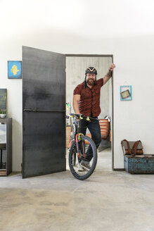 Porträt eines lächelnden Mannes mit Fahrrad im Büro - REAF00404