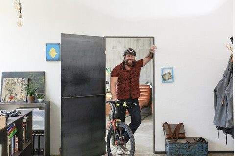 Porträt eines lachenden Mannes mit Fahrrad im Büro, lizenzfreies Stockfoto
