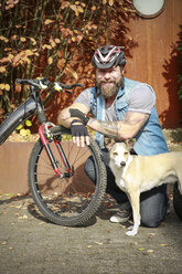 Porträt eines lächelnden Mannes mit Hund und Fahrrad - REAF00420