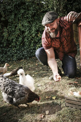 Mann in seinem eigenen Garten, Mann mit Ei von freilaufenden Hühnern - REAF00428