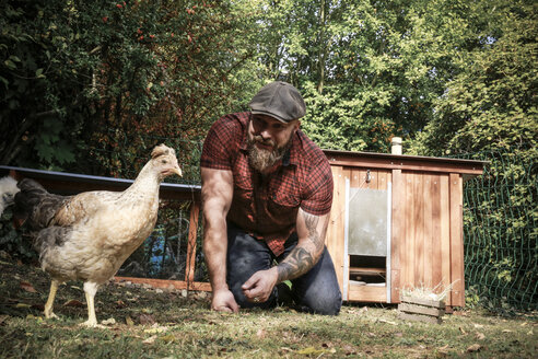 Man in his own garden, man feeding free range chicken - REAF00437