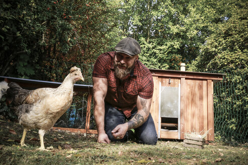 Mann in seinem eigenen Garten, Mann füttert freilaufende Hühner - REAF00437