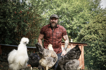 Mann in seinem eigenen Garten, freilaufende Hühner - REAF00439