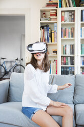 Mädchen sitzt zu Hause auf der Couch und benutzt eine Virtual-Reality-Brille - LVF07515