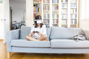 Mädchen sitzt zu Hause auf der Couch und benutzt eine Virtual-Reality-Brille - LVF07518