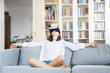 Mädchen sitzt zu Hause auf der Couch und benutzt eine Virtual-Reality-Brille - LVF07519