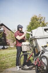 Cyclist recycling waste paper in paper bank - REAF00448