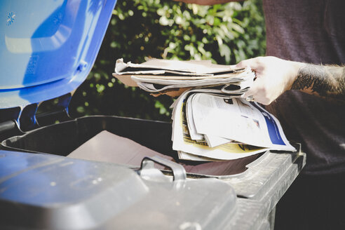 Tätowierter Mann recycelt Altpapier in einer Papierbank, Teilansicht - REAF00452