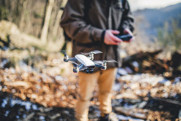 Mittelteil eines Wanderers, der einen Quadcopter im Wald fliegt - CAVF52642