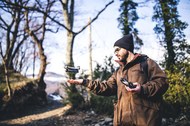 Männlicher Wanderer fliegt Quadcopter, während er im Wald steht - CAVF52645