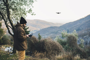 Seitenansicht eines männlichen Wanderers, der einen Quadcopter fliegt, während er auf einem Berg gegen den klaren Himmel steht - CAVF52653