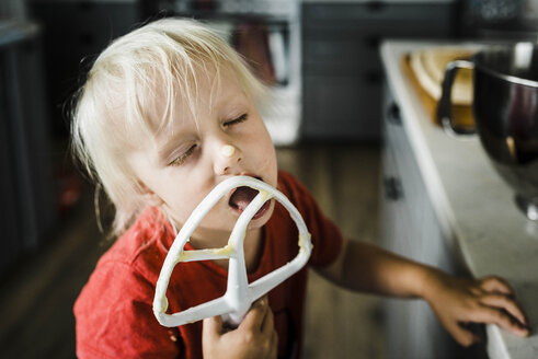 Close-up of girl with eyes closed licking food while standing in kitchen at home - CAVF52677
