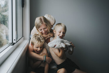 Happy mother with children sitting by window at home - CAVF52679