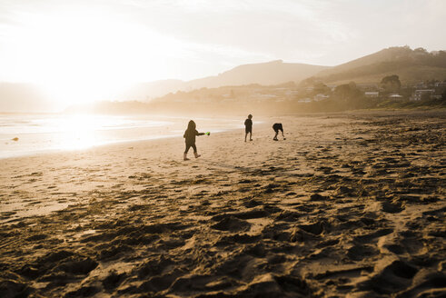 Silhouette Geschwister spielen am Strand gegen den Himmel bei Sonnenuntergang - CAVF52680
