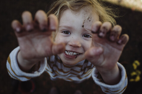 Hochformatiges Porträt eines glücklichen Mädchens, das auf einem Feld steht und gestikuliert, lizenzfreies Stockfoto